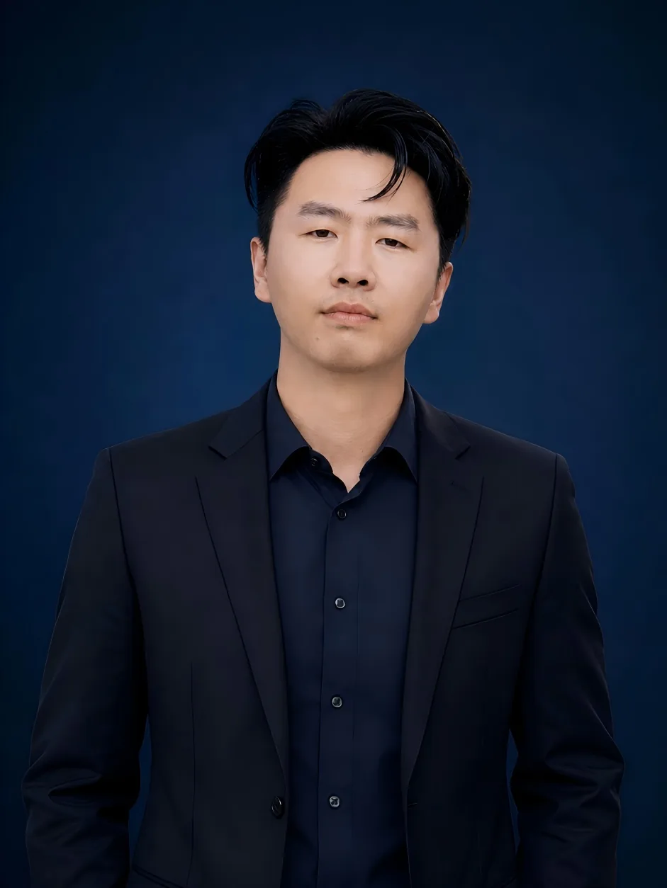 Formal portrait of our founder in a dark suit against a navy studio backdrop