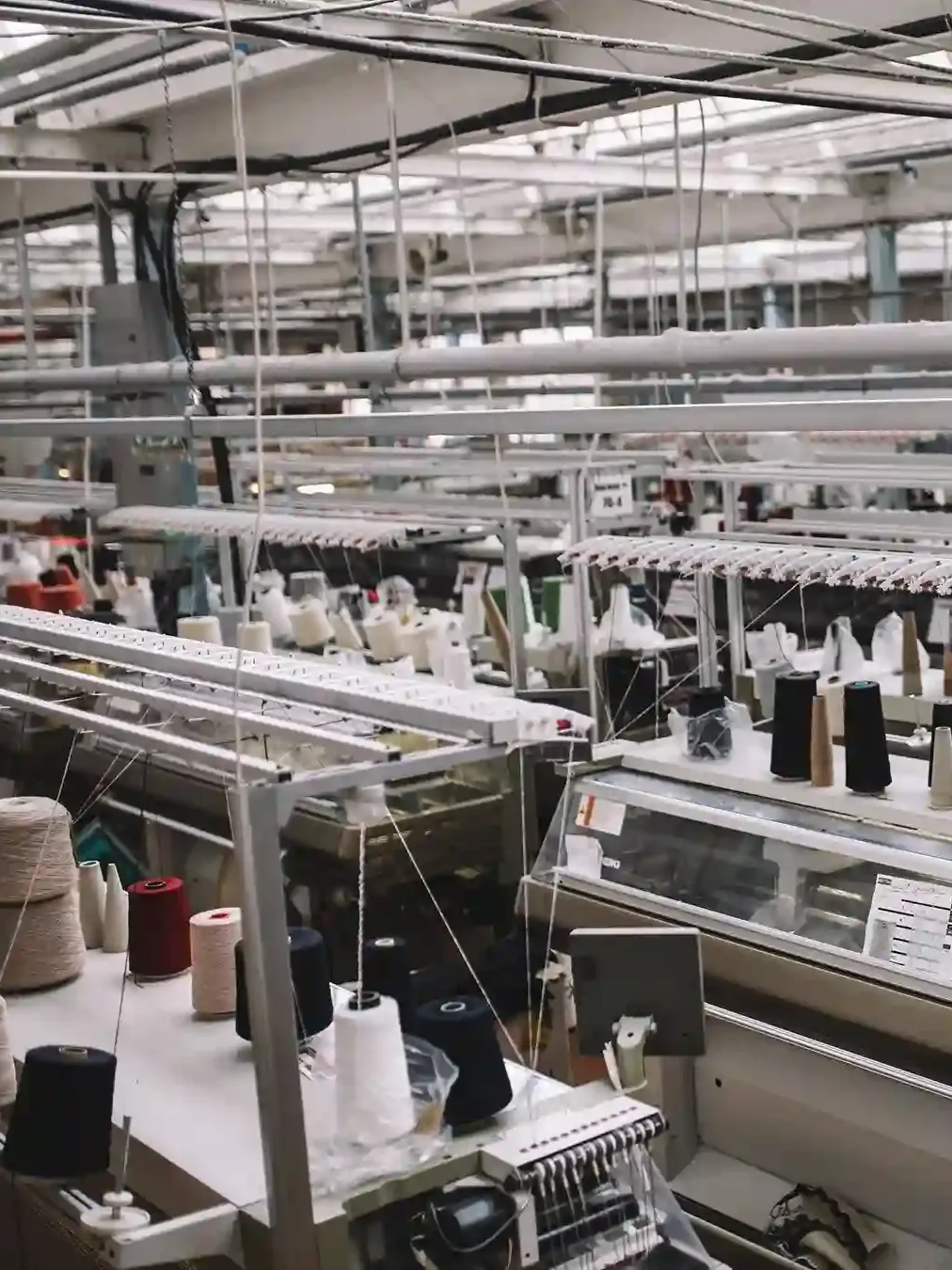 Knitting machines and yarn cones on a knitwear production floor